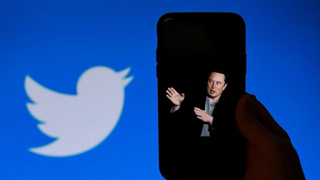 Elon Musk auf einem Handy. Im Hintergrund das Twitter Logo.