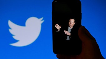 Elon Musk auf einem Handy. Im Hintergrund das Twitter Logo.