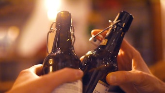 Zwei Menschen stoßen mit Bier in der Flasche an.