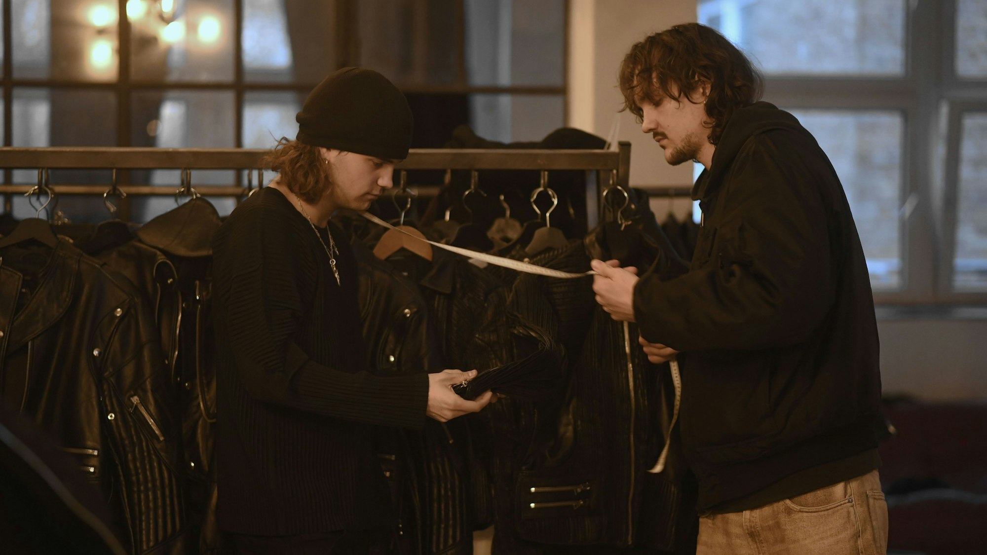 zwei Männer in dunkler Kleidung vermessen eine Lederjacke