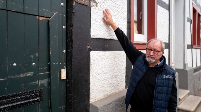 Robert Zimmermann zeigt an seinem Haus in Arloff, wie hoch das Wasser während der Flut 2021 stand. Dort ist auch eine Plakette angebracht worden, die das historische Hochwasser dokumentiert.