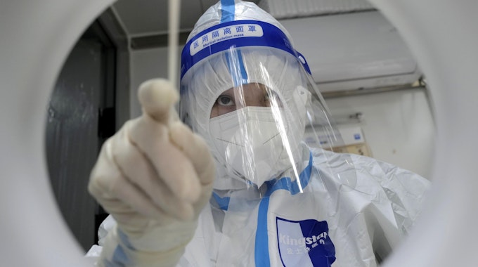Ein medizinischer Mitarbeiter in Schutzkleidung führt einen PCR-Test im Dezember 2022 in Shanghai zum Nachweis des Coronavirus durch. Wegen steigender Corona-Zahlen in China führt Italien und die USA nun eine Testpflicht für Reisende ein.