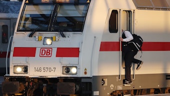 Ein Lokführer steigt am Bahnhof in einen Zug.