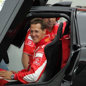 Michael Schumacher lachend am Steuer eines schwarzen Ferraris.