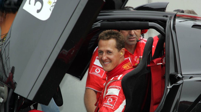 Michael Schumacher lachend am Steuer eines schwarzen Ferraris.