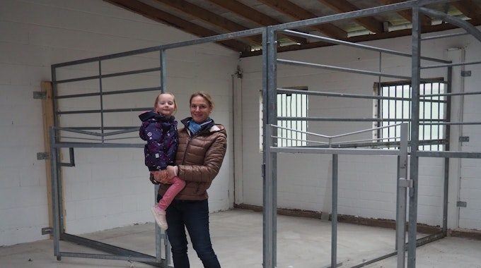 Das Bild zeigt Anne Spoo mit Tochter Paulina vor den Pferdeboxen.