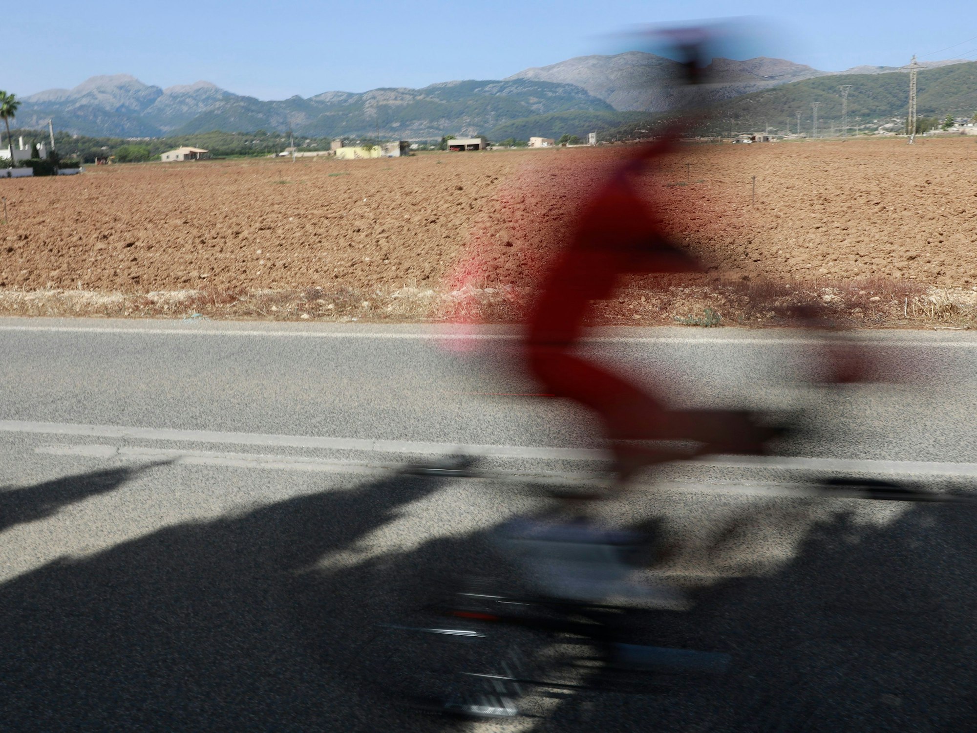 Ein Radfahrer fährt in Búger auf Mallorca eine Straße entlang.