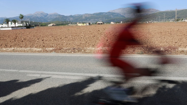 Ein Radfahrer fährt in Búger auf Mallorca eine Straße entlang.