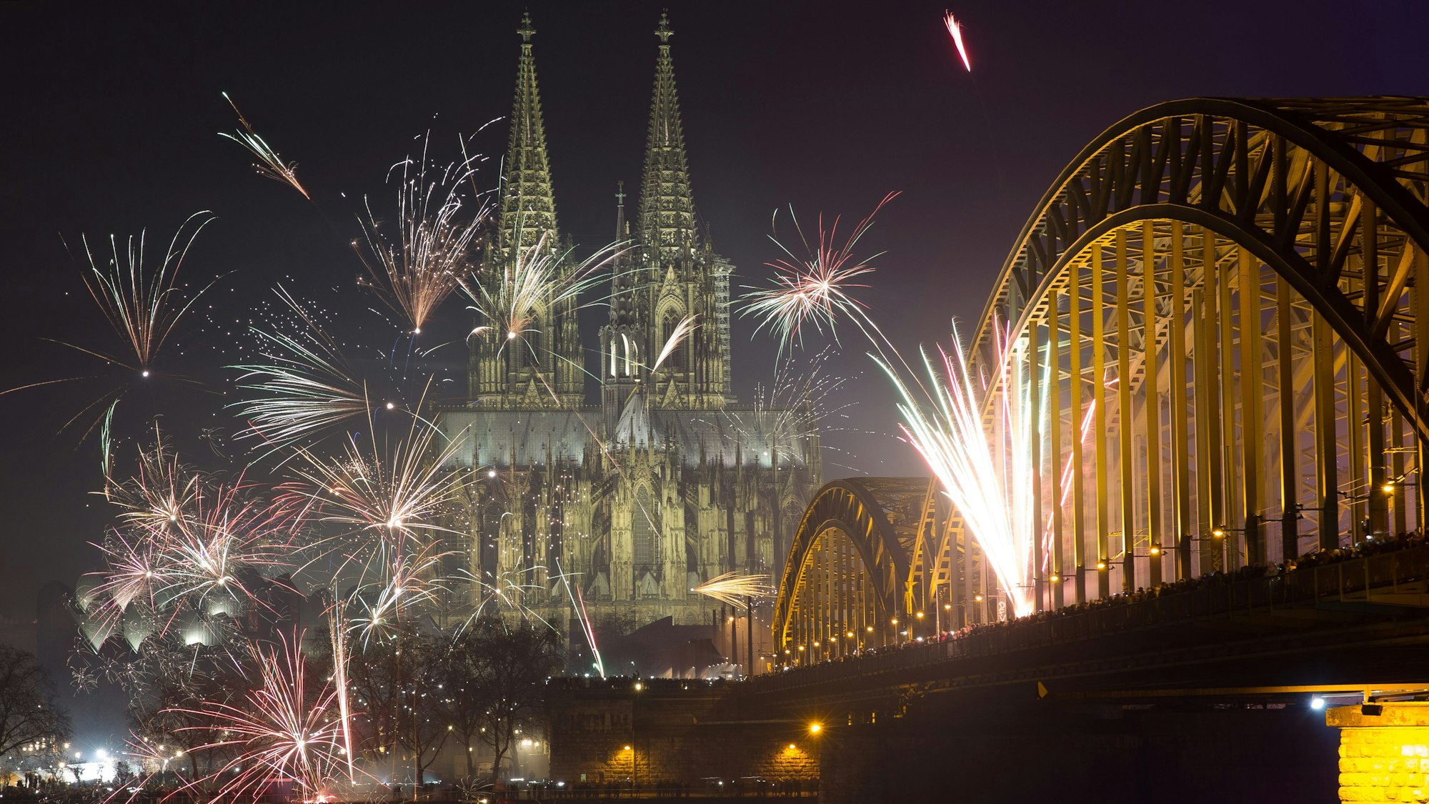 Feuerwerkskörper explodieren am in Köln (Nordrhein-Westfalen) über der Kulisse der Altstadt und des Doms.