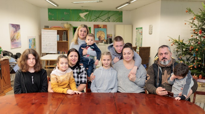 Zwei geflüchtete Familien aus der Ukraine sitzen an einem großen Tisch im Zentrum des Caritas-Verbandes in Gummersbach.