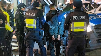 Kölner Polizisten führen einen Mann in Handschellen ab.