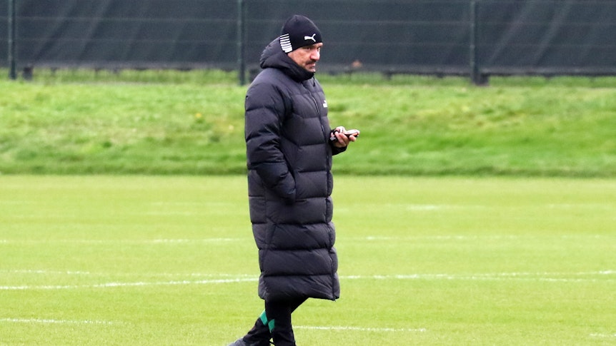 Trainer Daniel Farke beobachtet das Training von Borussia Mönchengladbach am 31. Dezember 2022. Farke trägt eine Mütze und eine knielange Jacke, in der linken Hand hält er eine Stoppuhr