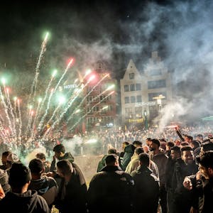 Böller und Feuerwerk explodieren in der Kölner Altstadt. Eine Menschenmenge, fast ausschließlich Männer, schaut zu.