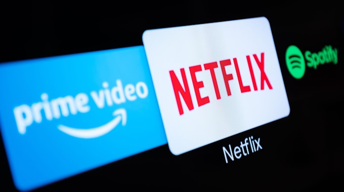 Auf einem Fernseher in einer Wohnung sind verschiedene Streaming-Dienste (Amazon Prime Video, Netflix, Spotify) geöffnet.