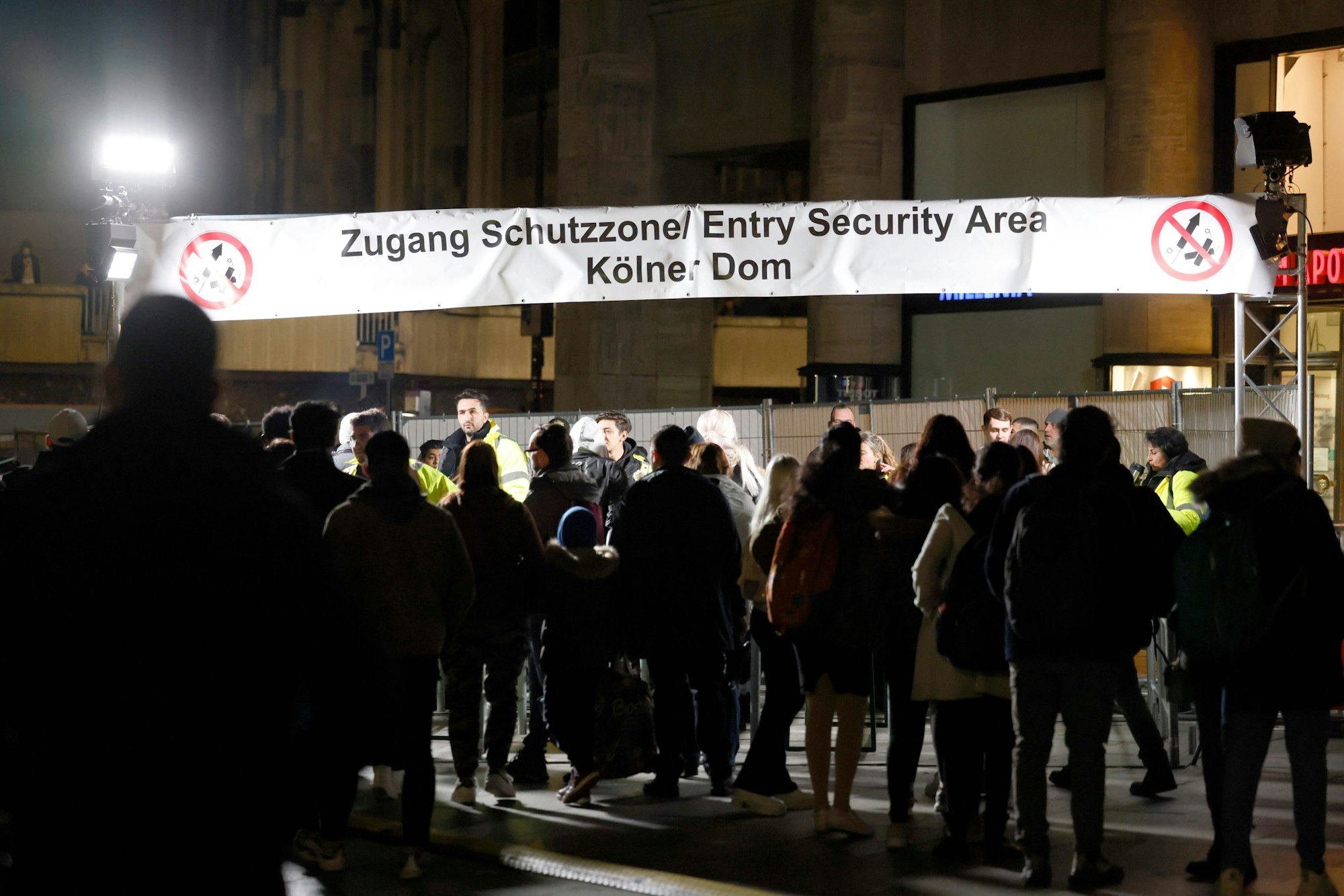 Ein lange Schlange Menschen steht am Eingang zur feuerwerksfreien Zone am Kölner Dom an.