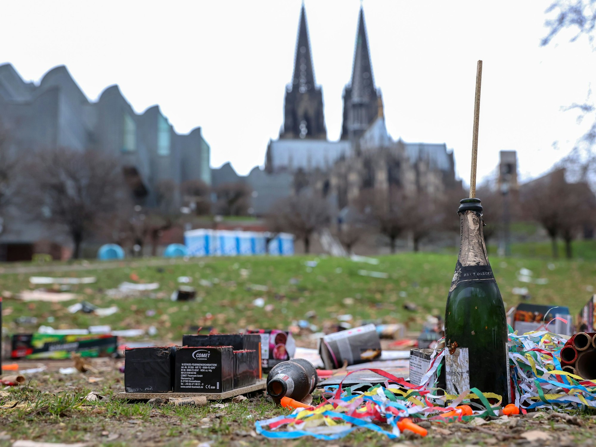 Das Bild zeigt im Vordergrund Müll von der Silvesternacht 2022/23. Im Hintergrund ist der Kölner Dom zu sehen.