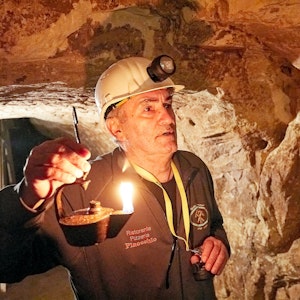 Ein Mann hält einen Grubenfrosch, die historische Öllampe der Bergleute.