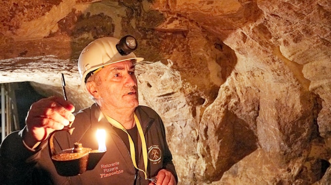 Ein Mann hält einen Grubenfrosch, die historische Öllampe der Bergleute.