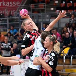 Eine Handballspielerin setzt sich gegen ihre Gegnerin durch und wirft.