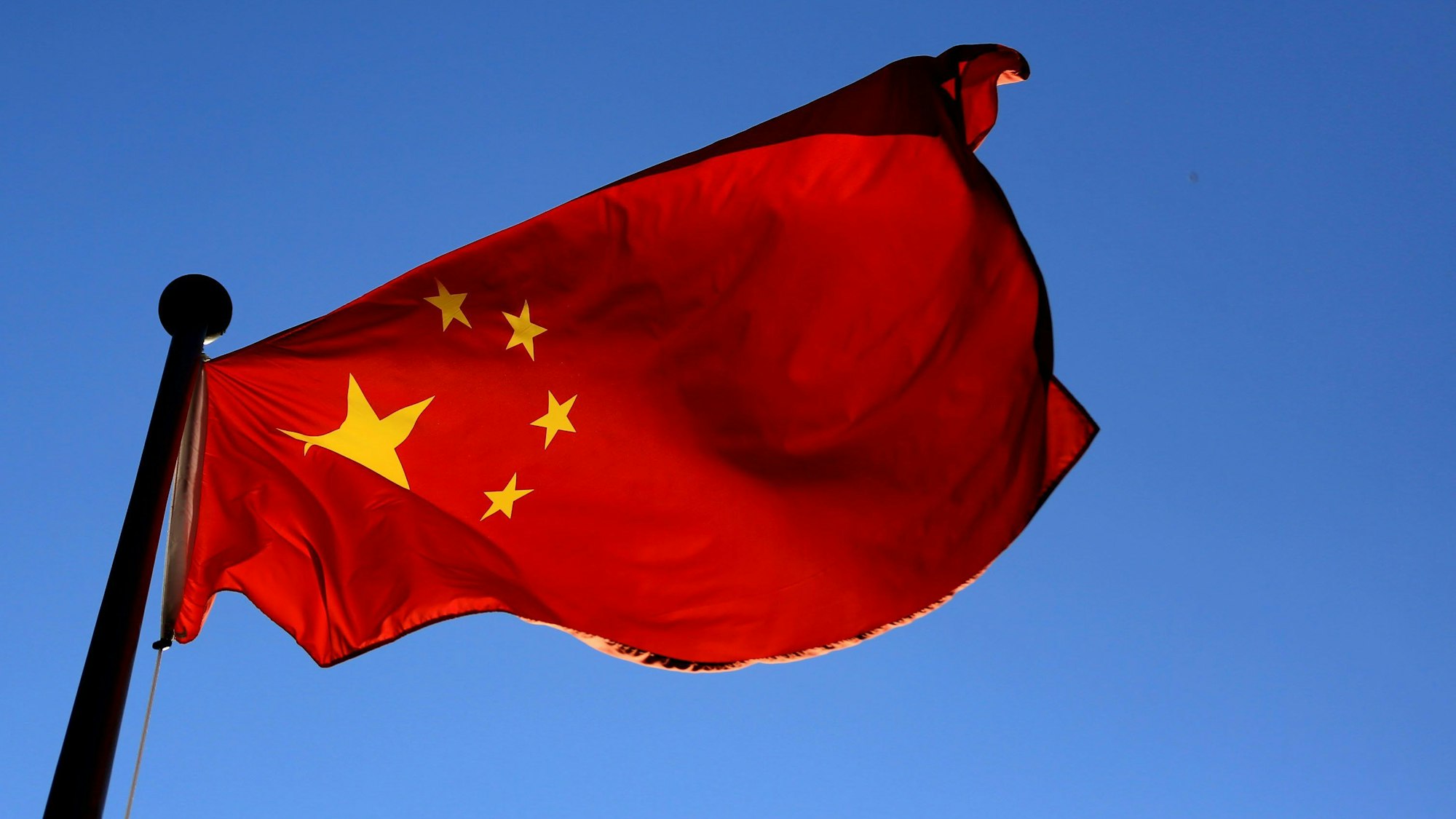 Man sieht die Flagge Chinas vor dem blauen Himmel.
