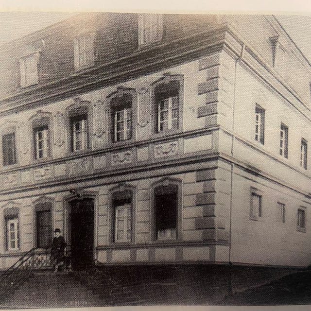Das Haus Boullé, damals an der Gütergasse neben der heutigen Klosterkapelle gelegen, in schwarz-weiß und mit einer Person vor der Tür.