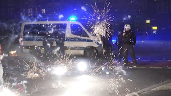 Polizeibeamte stehen in der Silvesternacht in Berlin hinter explodierendem Feuerwerk.