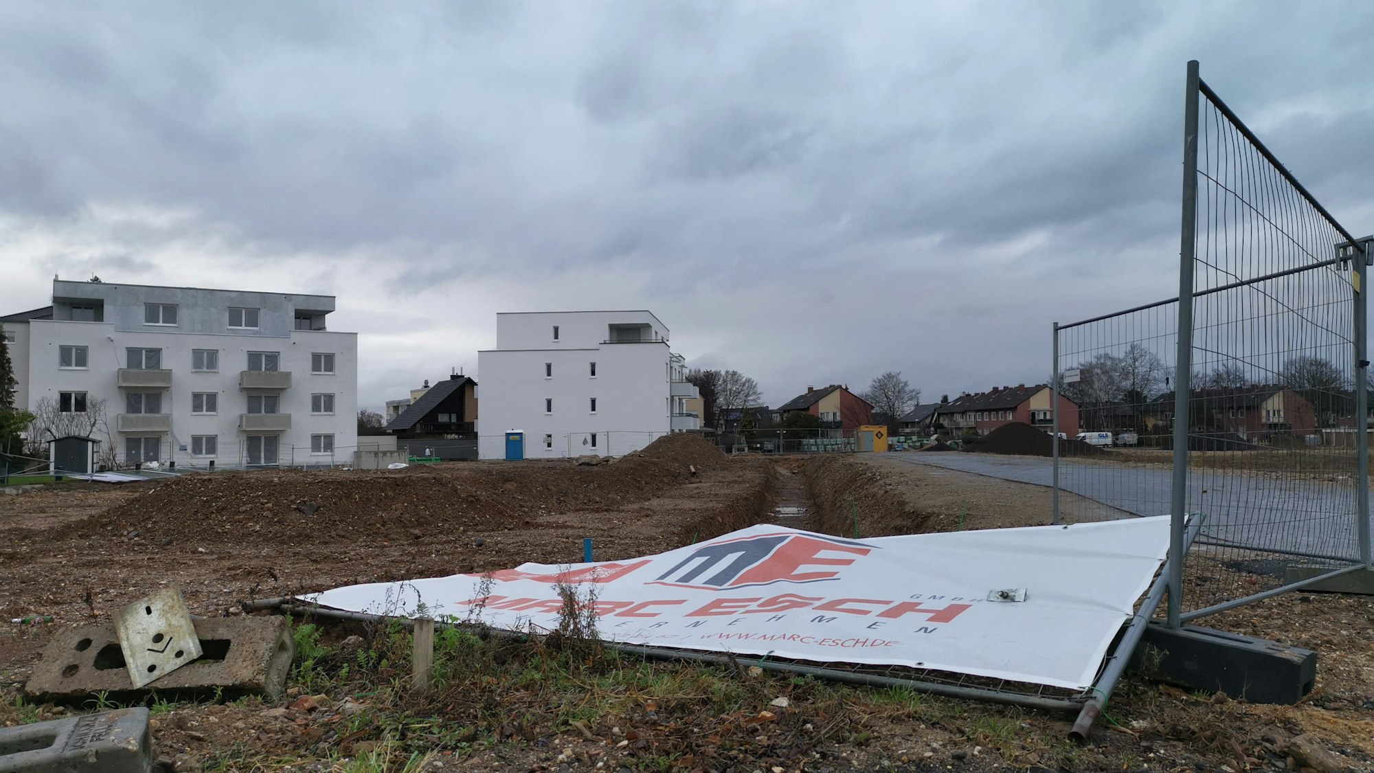 Wohnungsbau in Rheinbach: Ein Bauschild liegt umgestürzt auf einer Brachfläche.