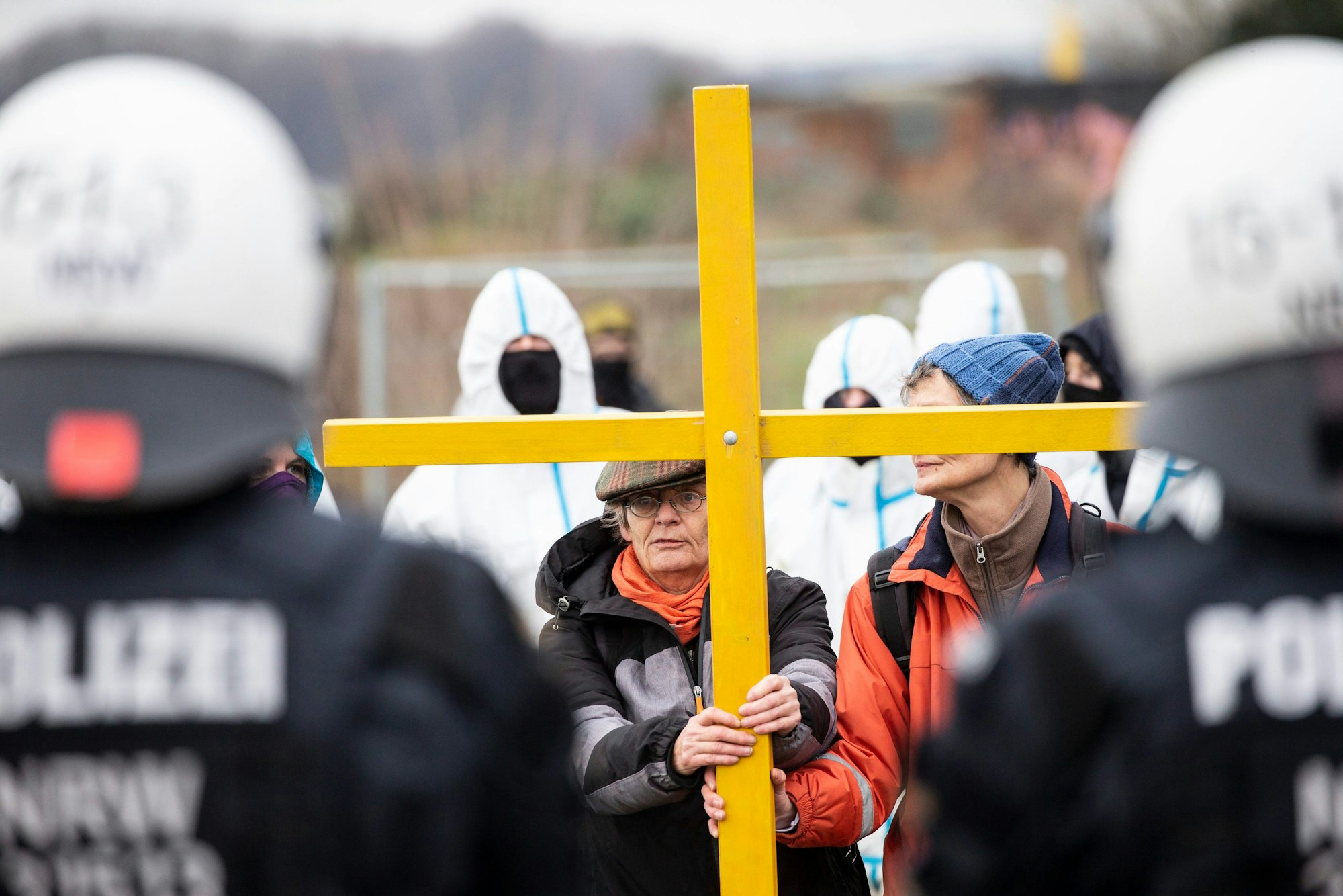 Während die Polizei Vorbereitungen zur geplanten Räumung des Dorfes Lützerath trifft, stellen sich Aktivisten mit einem Holzkreuz den Polizeibeamten entgegen.