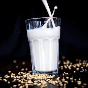 Siegeszug der Hafermilch: Ein Glas mit weißer Flüssigkeit, außen herum roher Hafer.