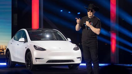 Tesla-CEO Elon Musk spricht beim „Cyber Rodeo“ im April 2022 in Texas. Hinter ihm steht ein weißer Tesla.