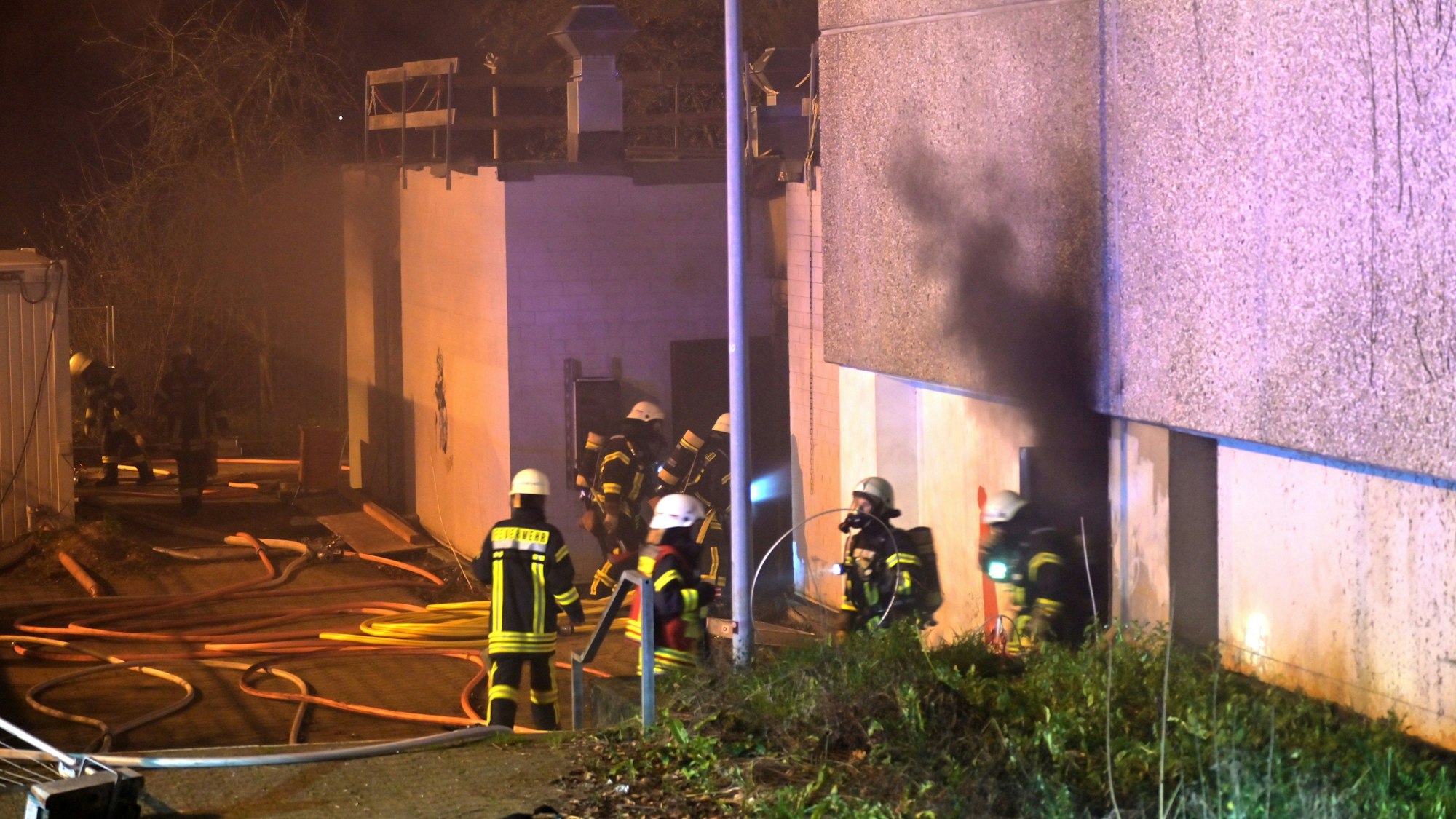 Die Sporthalle der Gesamtschule in Schlebusch brennt in der Nacht, Feuerlehrkräfte bekämpfen das Feuer.