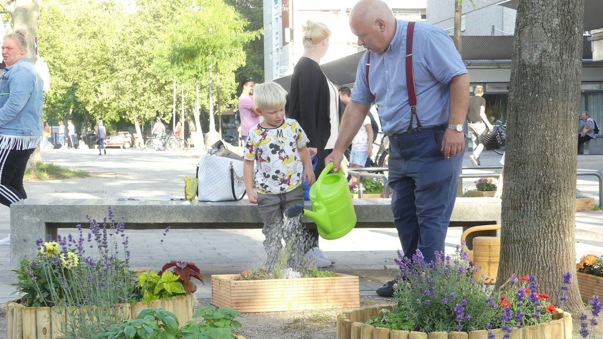 Streetworker Antonio Pizzulli steht mit einem kleinen Jungen in derBocklemünder Fußgängerzone und gießt dort selbst angelegte Blumenbeete.