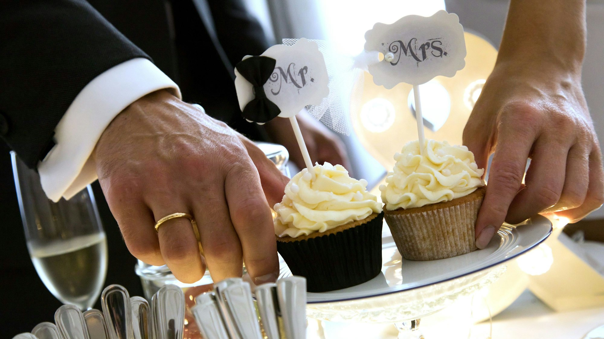 Ein Ehepaar hält zwei Muffins, auf denen steht „Mr. und Mrs.“.