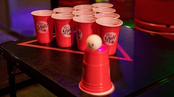 Rote Plastikbecher stehen in einem Dreieck auf einem Tisch. Der Aufbau eignet sich zum Beerpongspielen.