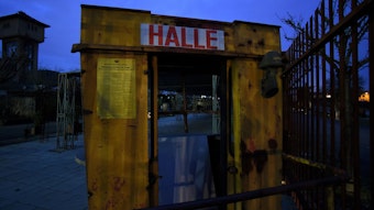 Schild der Halle Tor 2, dahinter im Dunkeln das Industriegelände.