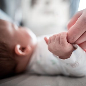 Ein Baby klammert sich an den Finger seiner Mutter.