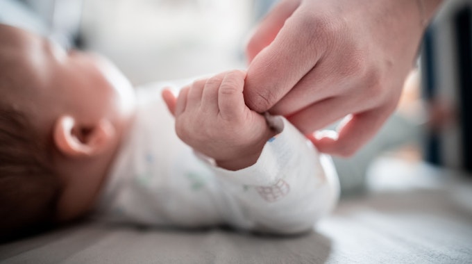 Ein Baby klammert sich an den Finger seiner Mutter.