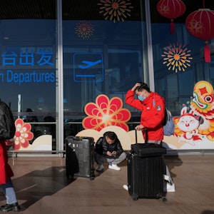 Reisende mit Mund-Nasen-Schutz rollen Gepäck am internationalen Abflugterminal am Hauptstadtflughafen.
