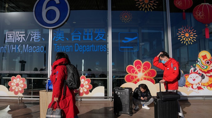 Reisende mit Mund-Nasen-Schutz rollen Gepäck am internationalen Abflugterminal am Hauptstadtflughafen.