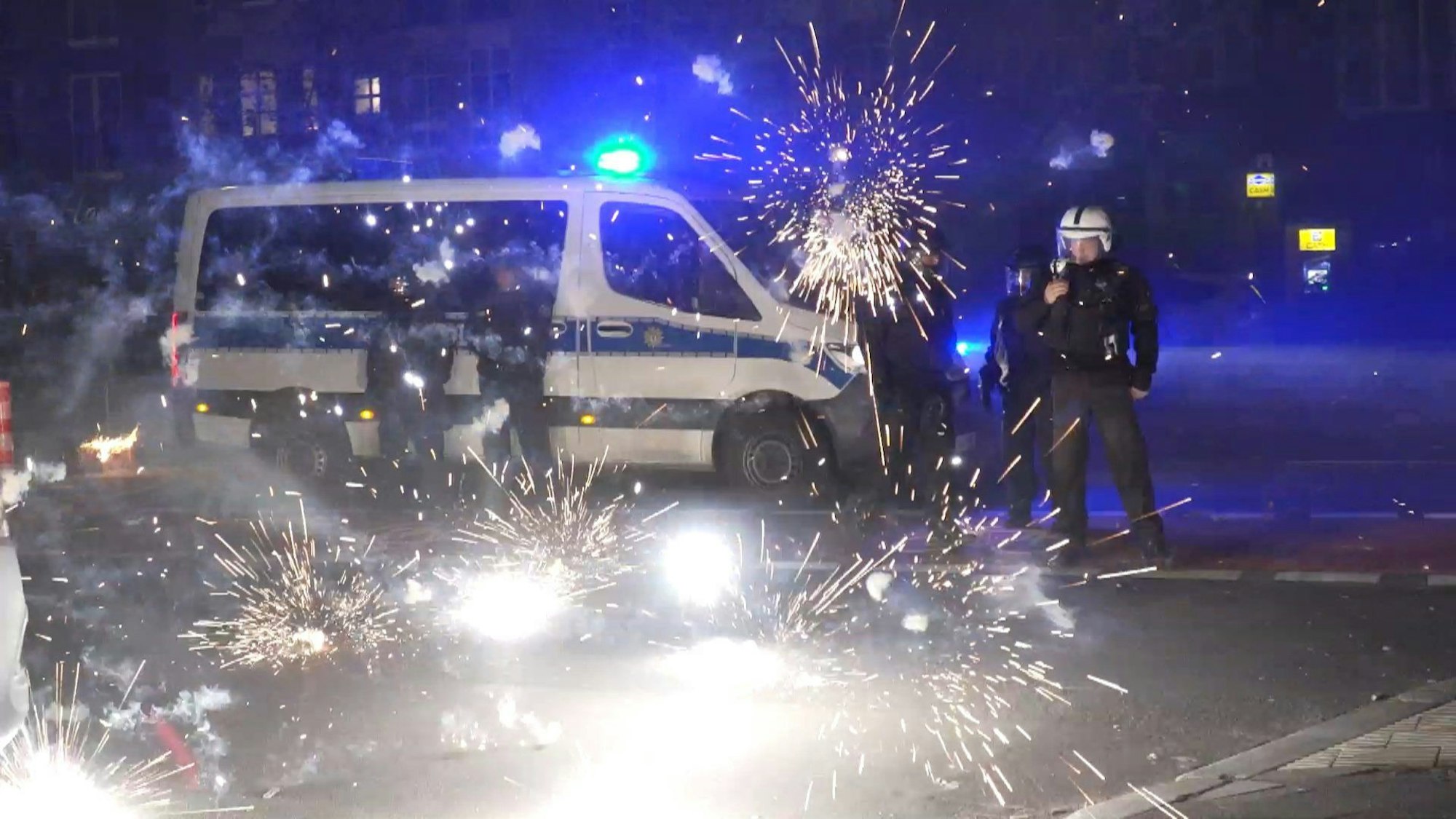 Polizeibeamte in Berlin stehen hinter explodierendem Feuerwerk.