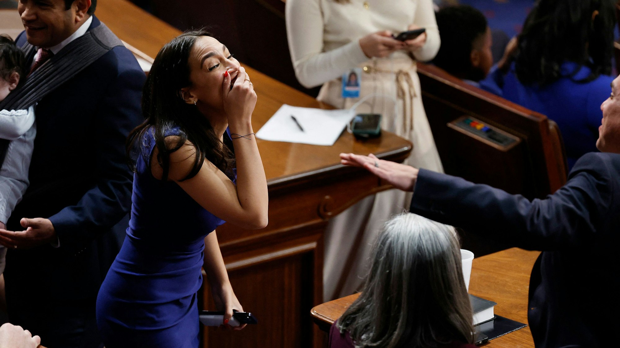 Die demokratische Abgeordnete Alexandria Ocasio-Cortez lacht im Repräsentantenhaus, nachdem es dem neuen Kongress nicht gelungen ist, einen Sprecher zu wählen. Die hält sich die Hand vor den Mund.