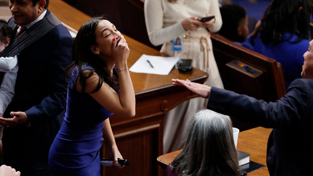 Die demokratische Abgeordnete Alexandria Ocasio-Cortez lacht im Repräsentantenhaus, nachdem es dem neuen Kongress nicht gelungen ist, einen Sprecher zu wählen. Die hält sich die Hand vor den Mund.