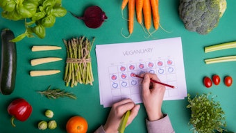 Jemand füllt einen Veganuary-Plan aus, darum liegt verschiedenen Obst und Gemüse.