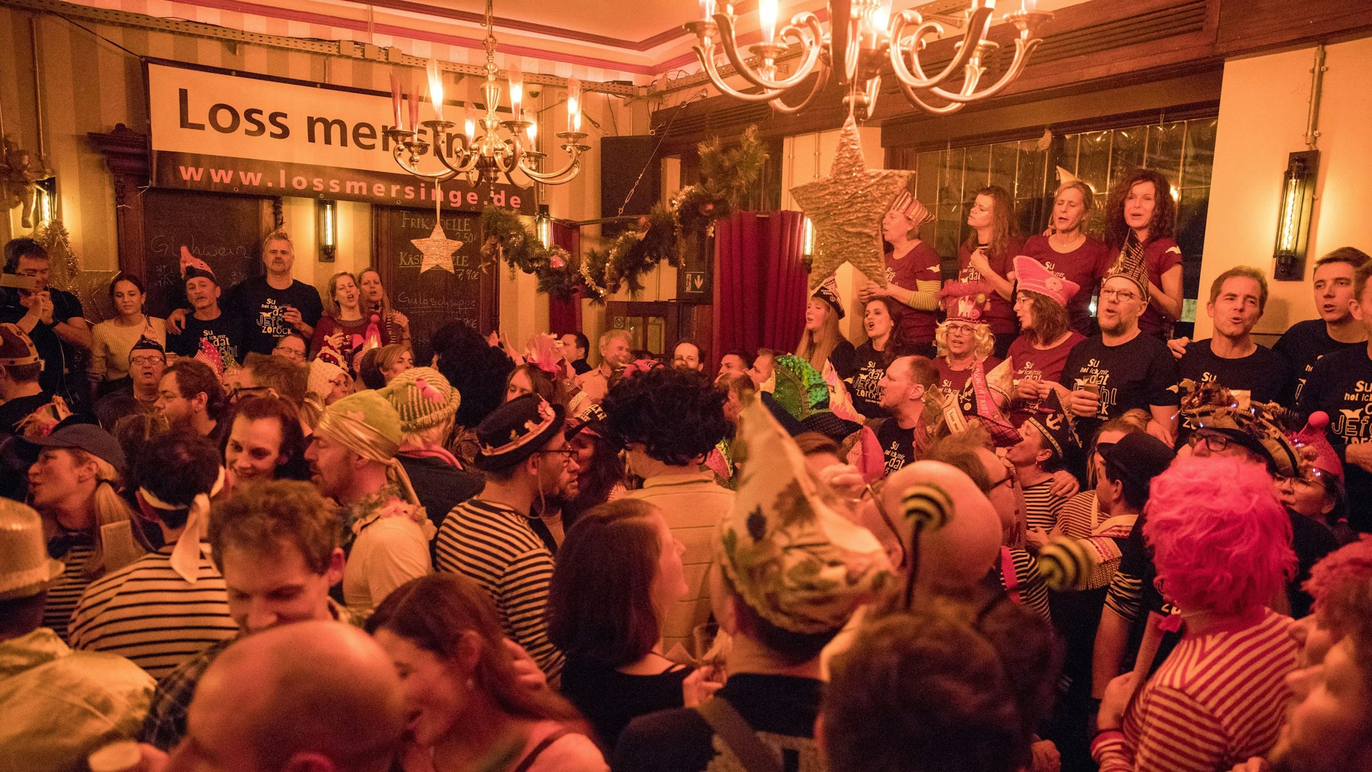 Menschen in Karnevalskostümen stehen dicht gedrängt in einer Kneipe.