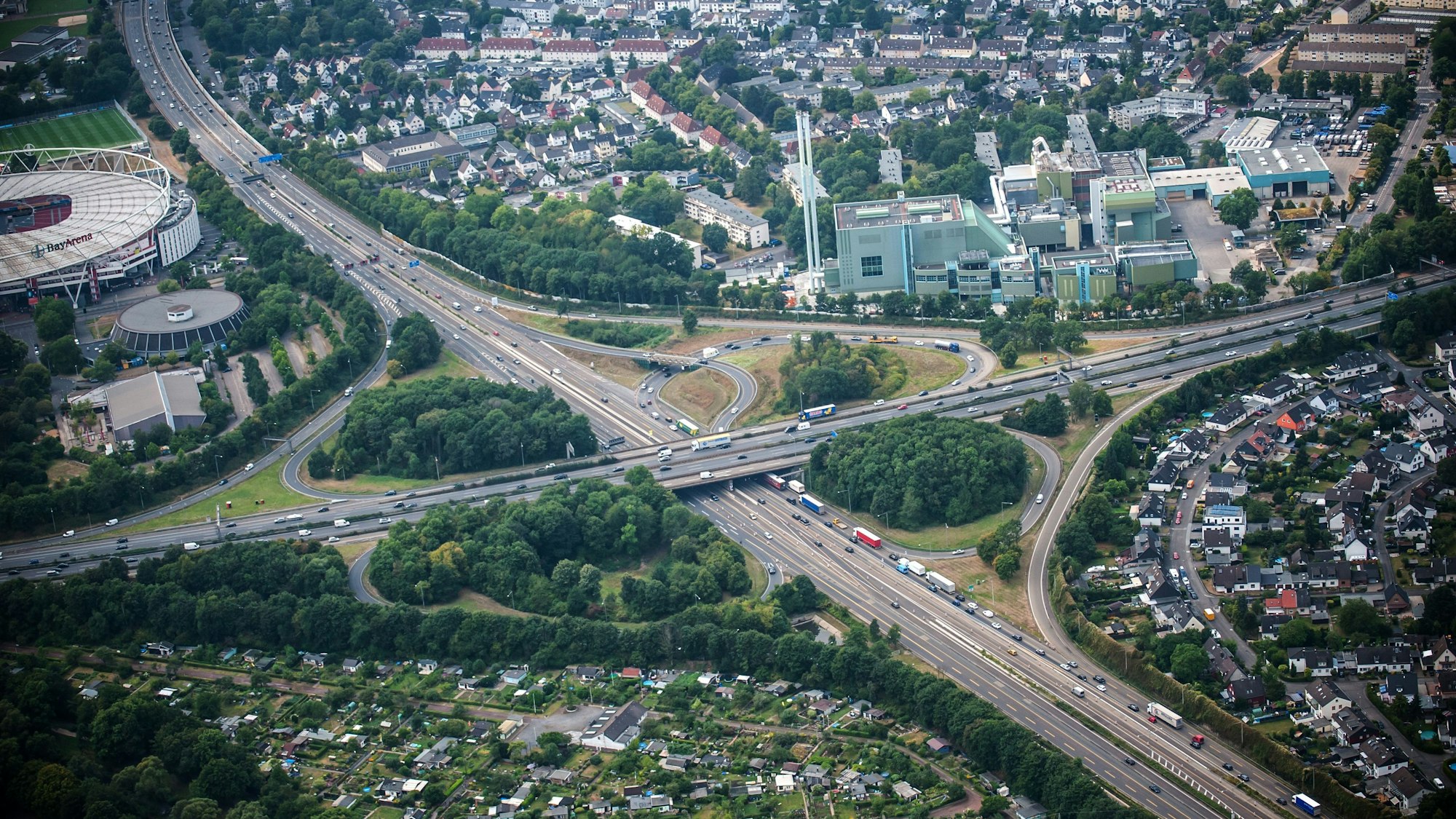 Luftbild des Autobahnkreuz Leverkusen mit den Autobahnen 1 und 3, links ist die Bayarena zu sehen. Auf einer Fahrspur stehen Fahrzeuge im Stau.