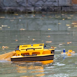 Das orange Boot auf dem Aachener Weiher. Rechts schwimmen Flaschen.