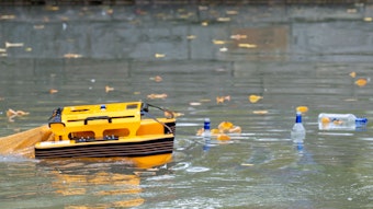 Das orange Boot auf dem Aachener Weiher. Rechts schwimmen Flaschen.
