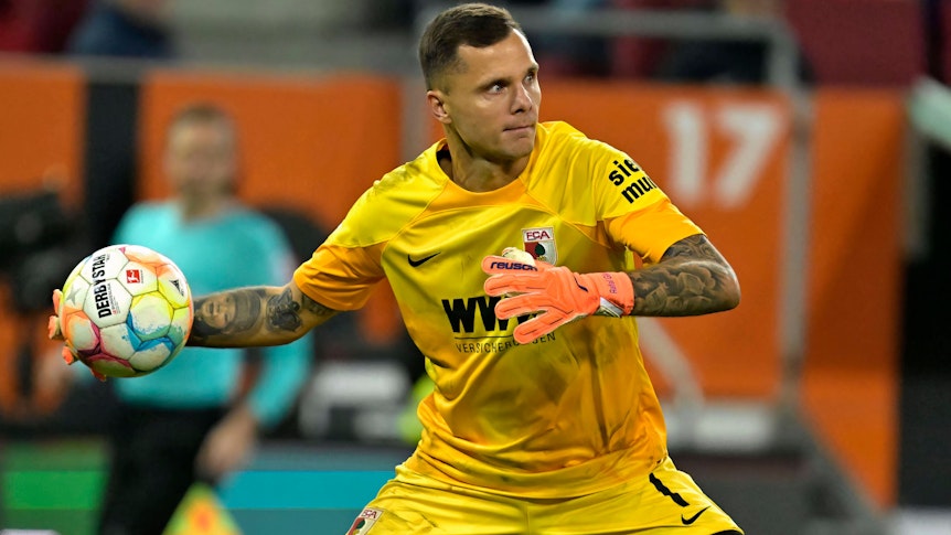 Torwart Rafal Gikiewicz vom FC Augsburg, hier beim Bundesliga-Spiel gegen den VfL Bochum am 12. November 2022, macht im gelben Trikot einen Abwurf.