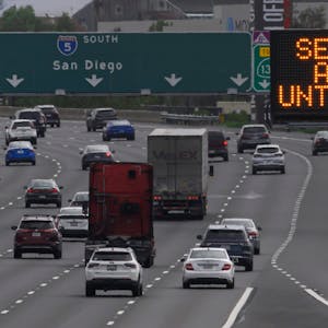 Ein Schild entlang der Interstate 5 warnt Autofahrer vor einem bevorstehenden Unwetter in Kalifornien. Mehrere Autos fahren über die Autobahn.