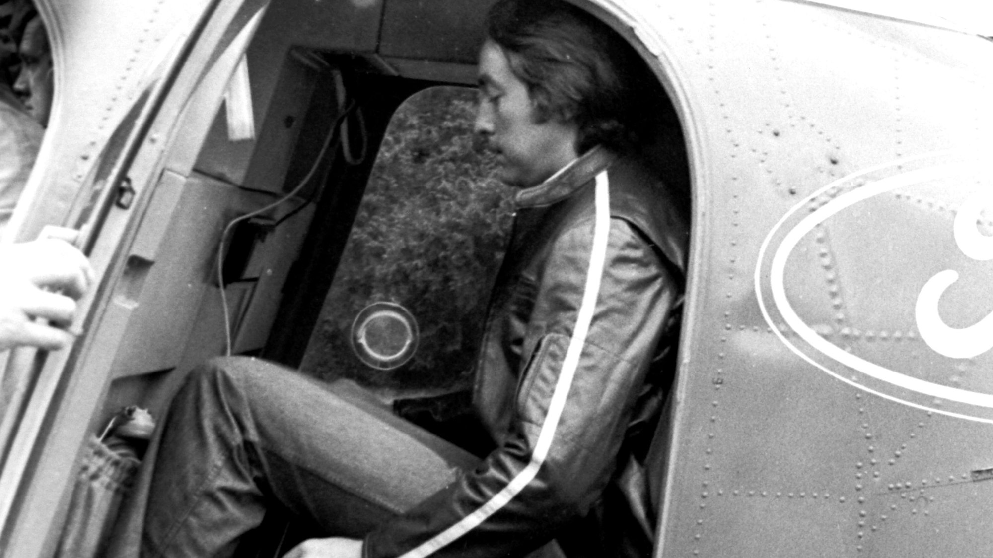 Emerson Fittipaldi sitzt in einem Hubschrauber. Das Bild ist schwarz-weiß.